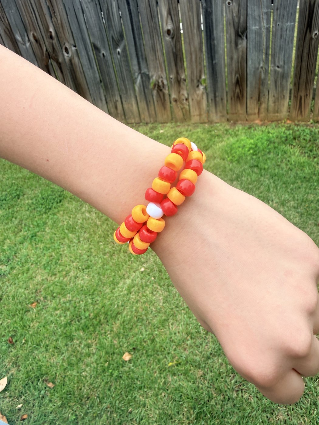 Red, orange, and white double helix pony bead bracelet worn on a wrist